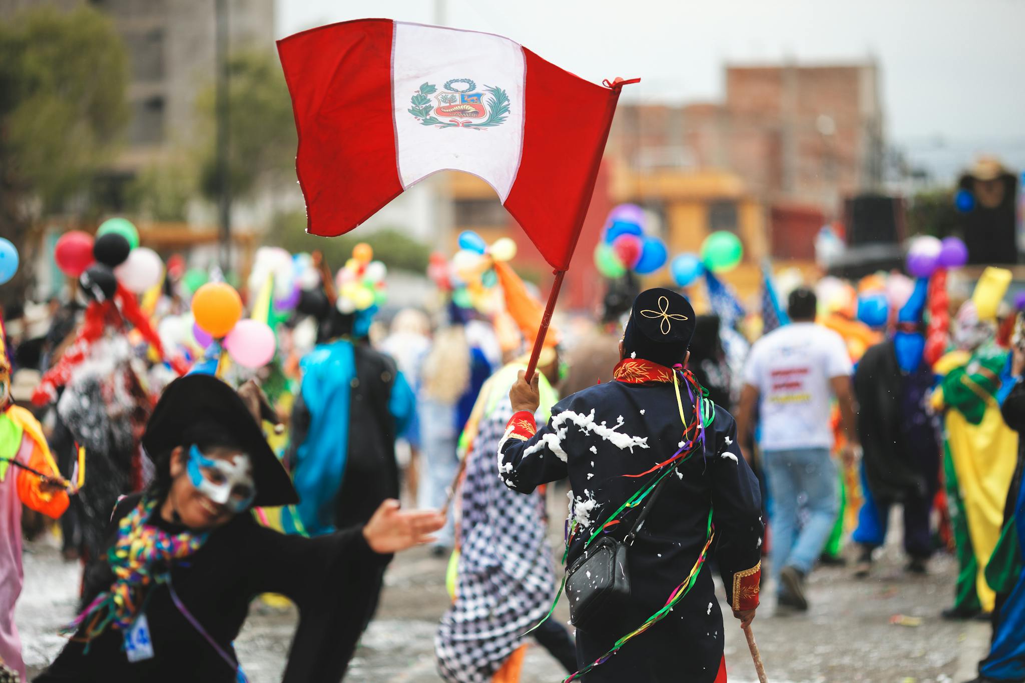 Colorful carnival scene in Arequipa, Peru with festive costumes and Peruvian flag.