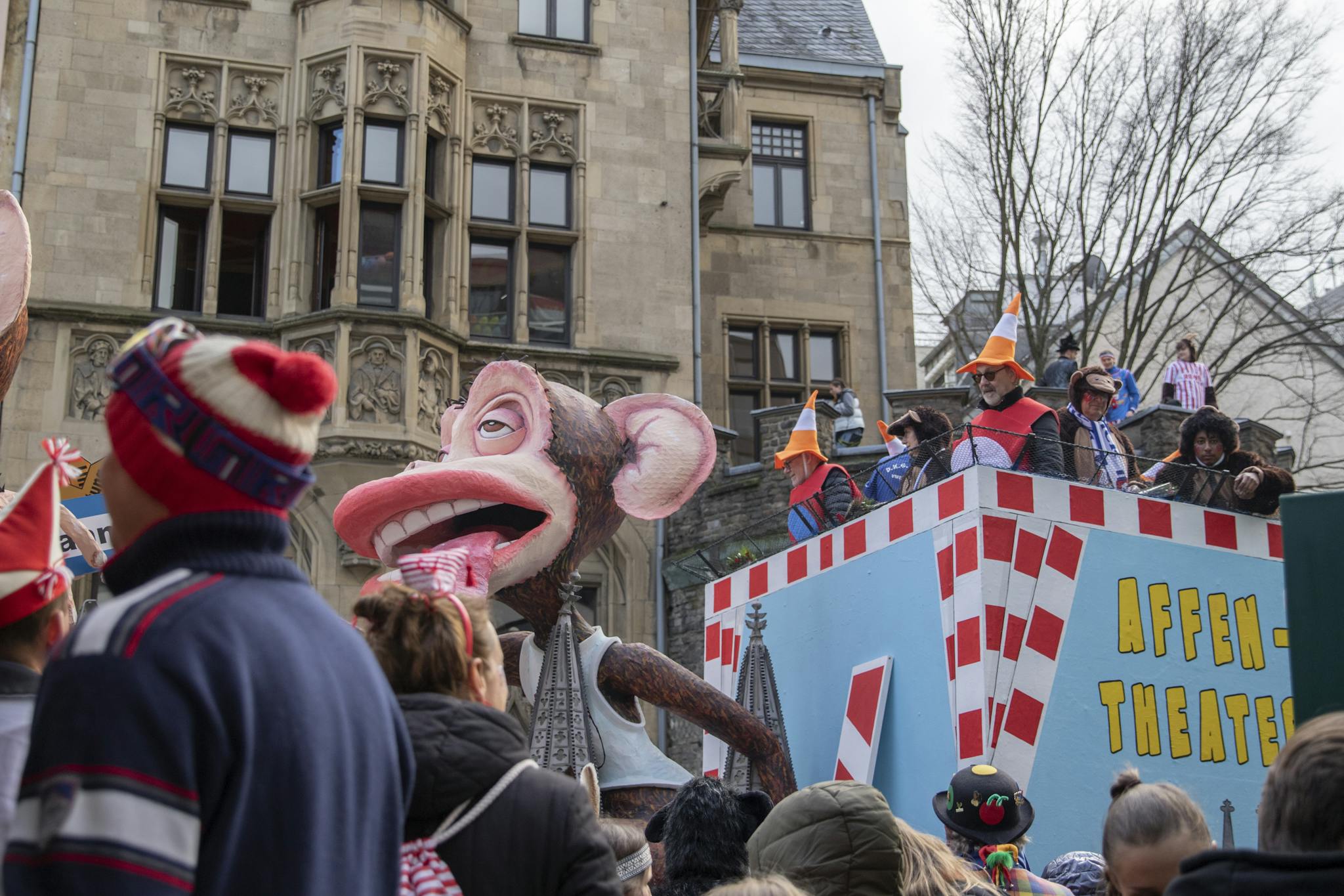 Vivid scene from Cologne Carnival parade featuring monkey float and costumed crowd.